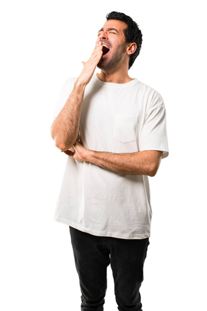 Νεαρός άνδρας με λευκό πουκάμισο χασμουρητό και καλύπτοντας το ορθάνοιχτο στόμα με το χέρι. Νυσταγμένος έκφραση σε απομονωμένες άσπρο φόντο - Φωτογραφία, εικόνα