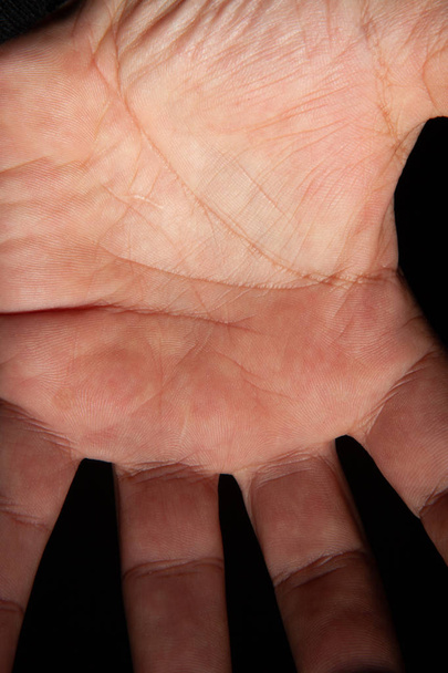 menschliche Hand wird durch Licht auf schwarzem Hintergrund gezeichnet, Machtkonzept, Handfläche eines Mannes, Nahsicht - Foto, Bild