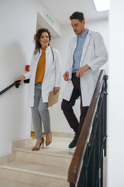 Mies ja nainen lääkäri kävelemässä portaita alas ja puhumassa
. - Valokuva, kuva