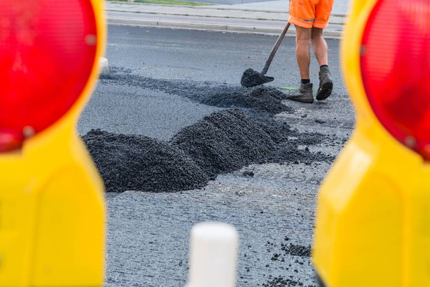 Trabalhadores rodoviários distribuir o asfalto quente com pás na estrada, Alemanha
 - Foto, Imagem