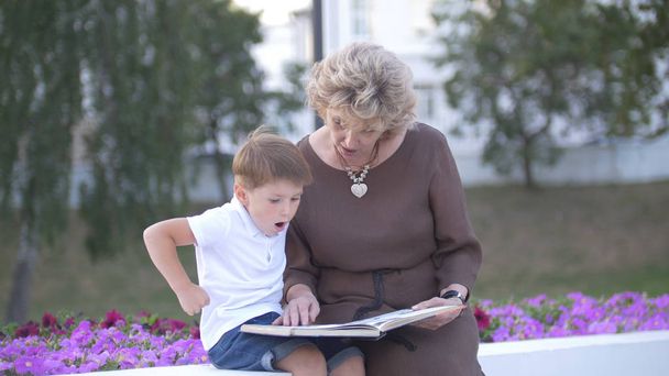 Isoäiti pojanpojan kanssa lukemassa kirjaa yhdessä
 - Valokuva, kuva