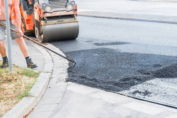 Road werknemers verspreiding warm asfalt met schoppen en rollen op de weg, Duitsland - Foto, afbeelding