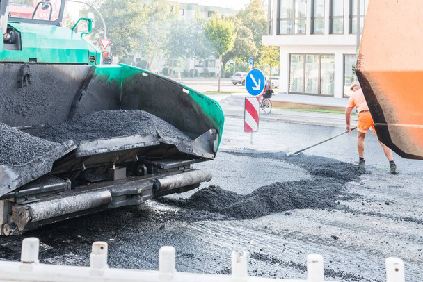 Close-up van een asfalt bestratingsafwerkmachines op een bouwplaats vernieuwing van het wegdek, Duitsland - Foto, afbeelding