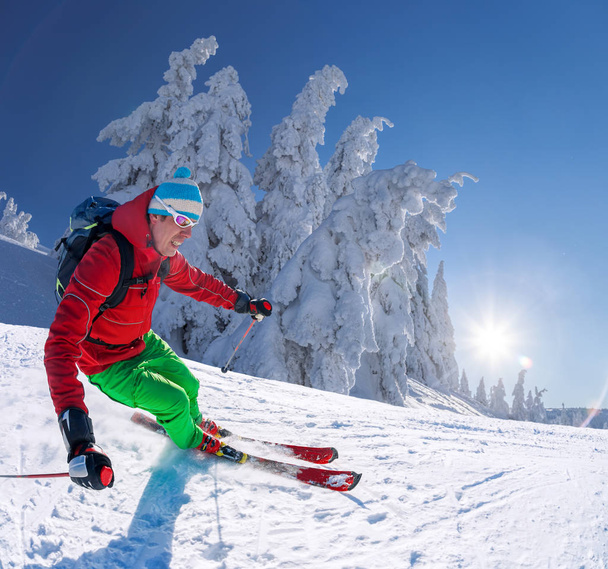 Skiër skiën afdaling in hoge bergen tegen blauwe hemel - Foto, afbeelding