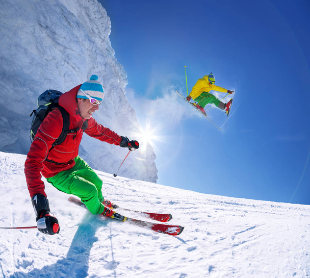 Esquiador esquiando cuesta abajo en las altas montañas contra el cielo azul
 - Foto, imagen