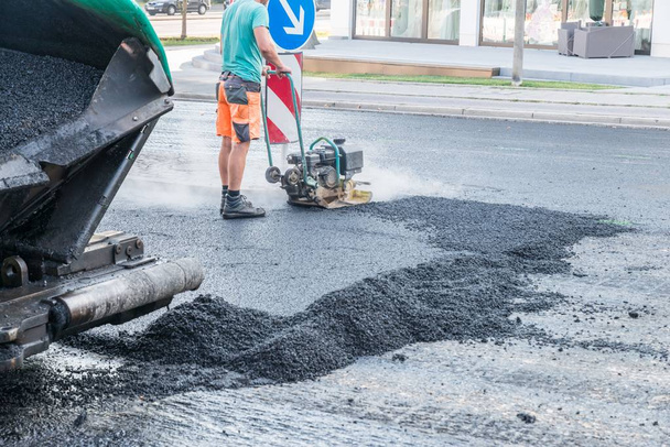Road werknemers compact het asfalt met een trillende stamper met een doorsnee onderweg, Duitsland - Foto, afbeelding