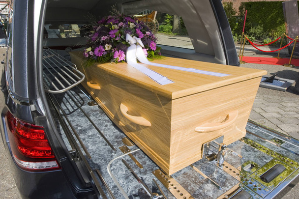 A coffin with a flower arrangement in a funeral car - Photo, Image