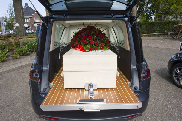 A coffin with a flower arrangement in a funeral car - Photo, Image