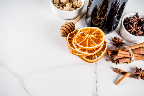 Ingredients for traditional autumn drink, mulled wine cocktail - red wine, stale oranges, cane sugar, honey, cinnamon, spices, anise, on white marble background, top view space for text - Photo, Image