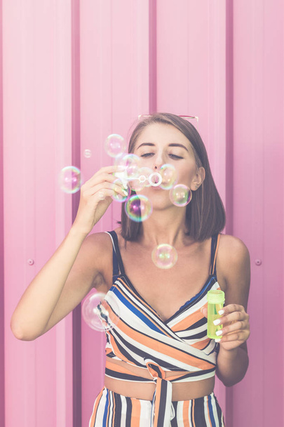 Woman playing with soap balloons on pink background. - Fotografie, Obrázek