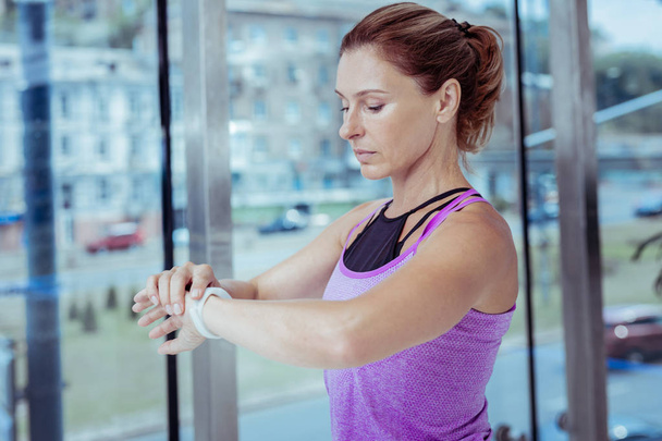 Attente volwassen vrouw controleren puls in sportschool - Foto, afbeelding