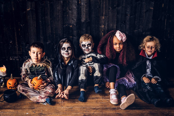 Cadılar Bayramı partisi grup çocukları ile birlikte eski bir evde bir ahşap zemin üzerinde oturan. Cadılar Bayramı kavramı. - Fotoğraf, Görsel