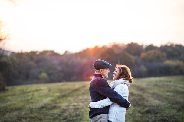 Senior couple hugging in an autumn nature at sunset. - Фото, зображення