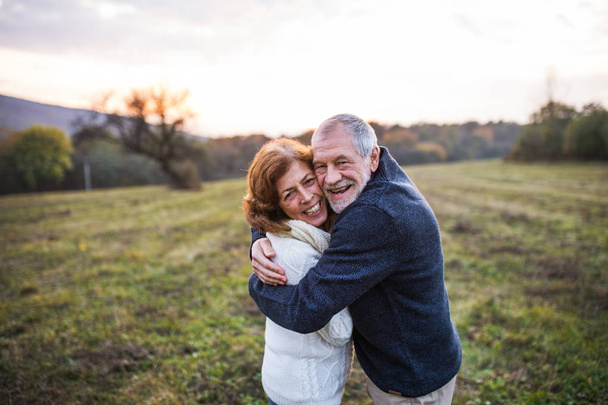 Senior couple hugging in an autumn nature at sunset. - 写真・画像