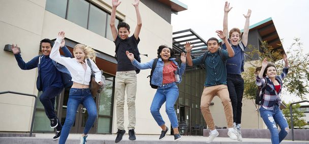 Group Of High School Students Jumping In Air Outside College Buildings - 写真・画像