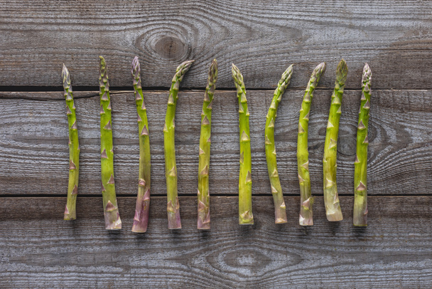 top view of green asparagus on grey wooden tabletop - Foto, Imagen