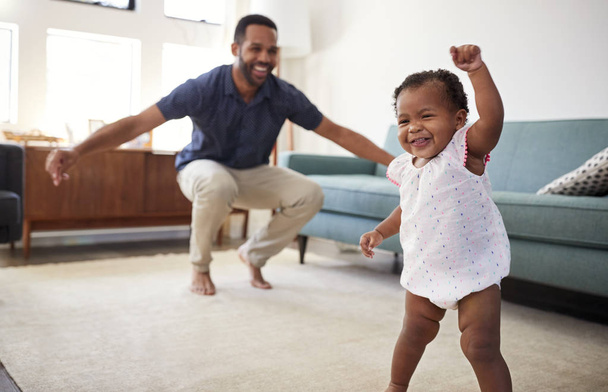 Baby Daughter Dancing With Father In Lounge At Home - Foto, immagini