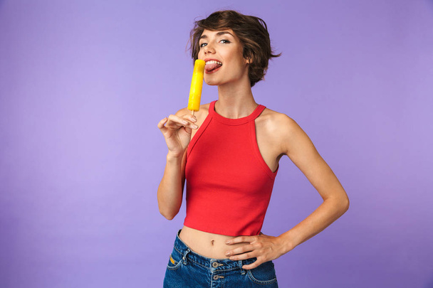 Image of positive cute woman 20s in casual wear smiling and eating ice cream isolated over violet background - Valokuva, kuva