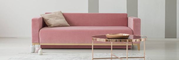 Pink sofa with cushion in real photo of bright sitting room interior with rose gold end table with decorative plate - Valokuva, kuva
