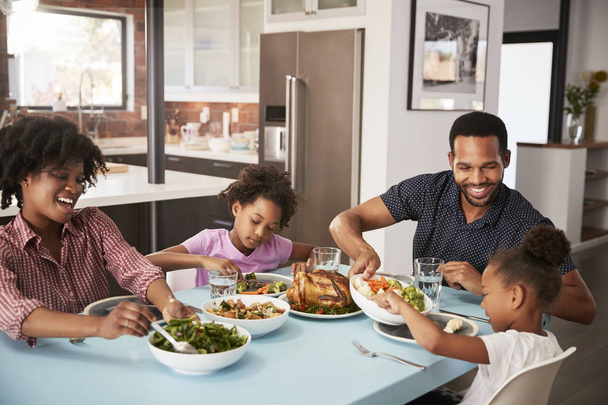 Família desfrutando de refeição em torno da mesa em casa juntos
 - Foto, Imagem