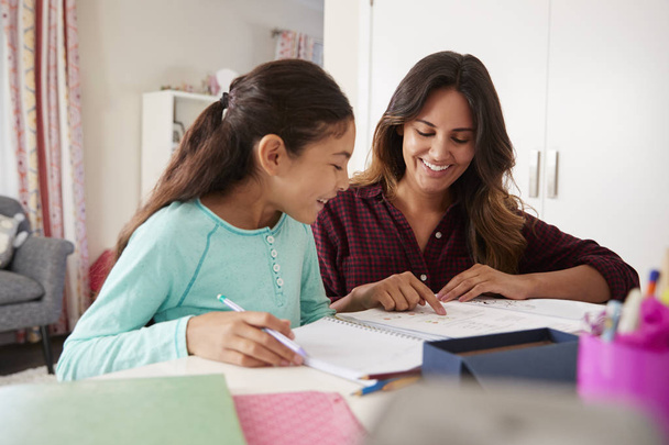 Mother Helping Daughter With Homework Sitting At Desk In Bedroom - Foto, immagini