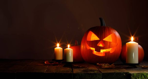 Halloween pumpkin head jack o lantern and candles on wooden background - Photo, image
