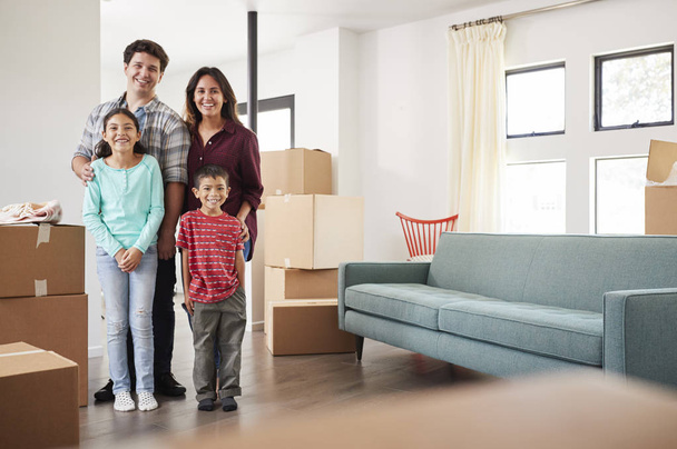 Happy Family Surrounded By Boxes In New Home On Moving Day - Photo, image