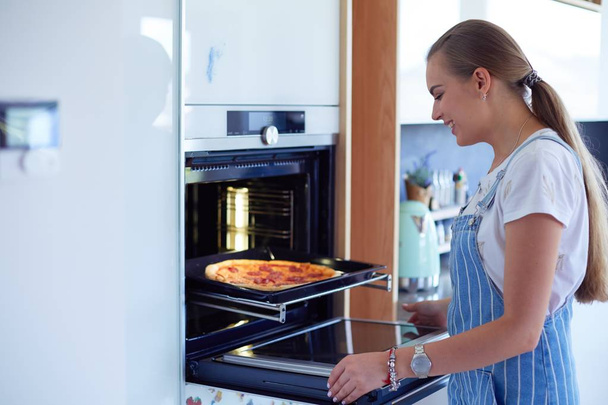 Щаслива молода жінка готує піцу вдома
 - Фото, зображення