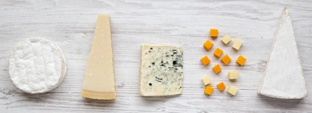 Sortiment různých sýrů na bílé dřevěné povrchu, horního pohledu. Z výše uvedeného ploché lay. - Fotografie, Obrázek