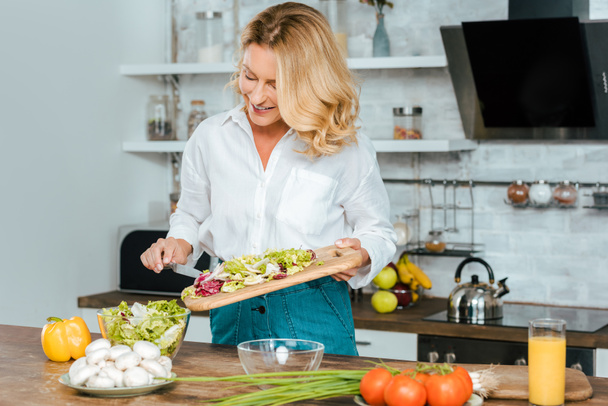 beautiful adult woman making healthy salad at kitchen - Foto, Imagem
