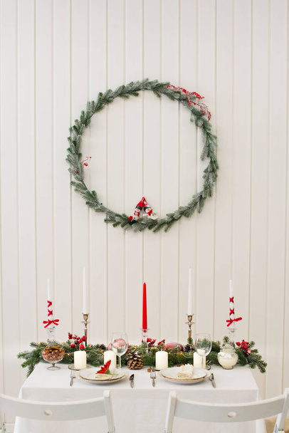 Різдвяний або новорічний інтер'єр. Гарний стіл для пари з різдвяними прикрасами на і вище, оригінальні свічки і тонкий вінок з різдвяними ляльками
 - Фото, зображення
