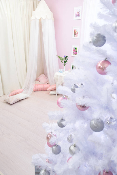 白から女の子らしい明るいピンクの部屋のビューには、クリスマス ツリーが飾られています。クリスマスと新年装飾インテリア ルーム - 写真・画像