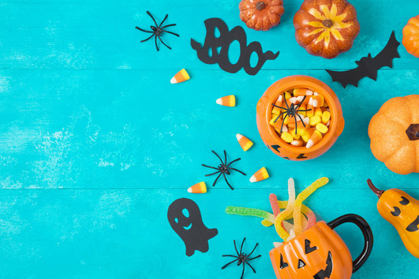 Halloween holiday background with jack o lantern pumpkisn, candy corn and decorations on blue wooden board. View from above. Flat lay - Photo, image