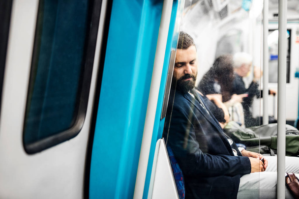 Sleeping hipster businessman inside the subway in the city, travelling to work. - 写真・画像
