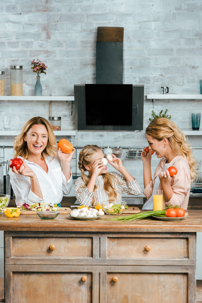 child playing with food with mother and grandmother while cooking - Photo, Image