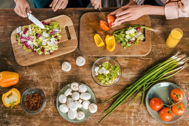 plan recadré de femmes et d'enfants coupant des légumes pour salade sur table rustique
 - Photo, image