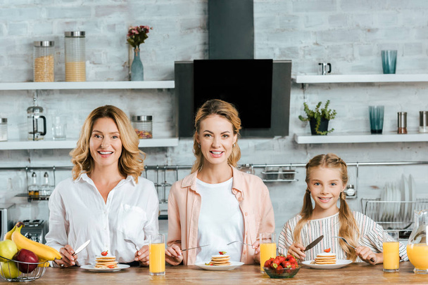 schöne drei Generationen von Frauen mit Pfannkuchen zum Frühstück zu Hause vor der Kamera - Foto, Bild