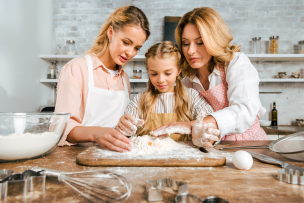 imádnivaló gyermek anyja és nagyanyja így tésztát liszttel és a tojással együtt otthon - Fotó, kép