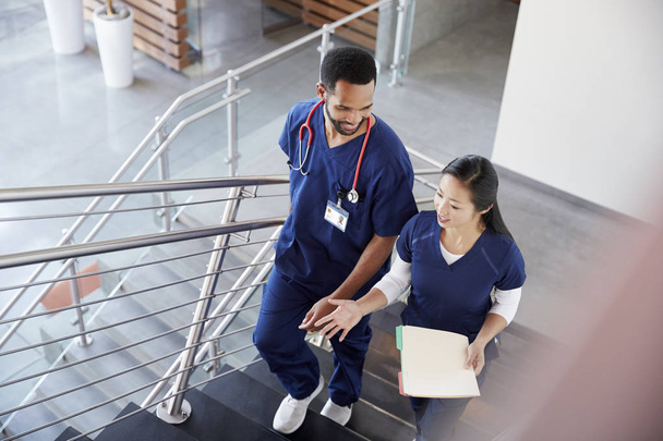 Kaksi terveydenhuollon kollegaa puhuu portaissa sairaalassa
 - Valokuva, kuva
