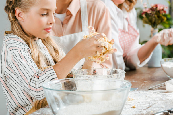 cropped shot of adorable little child making dough with parents at home - Valokuva, kuva