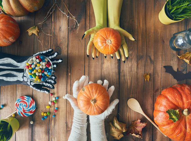 Happy halloween! Hands and pumpkins on the table in the home. Family preparing for holiday. Top view. Close up. - Fotoğraf, Görsel
