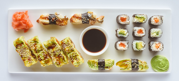 Προβολή με μεγέθυνση νόστιμο σούσι με τζίντζερ, wasabi και σάλτσα σόγιας που απομονώνονται σε λευκό  - Φωτογραφία, εικόνα