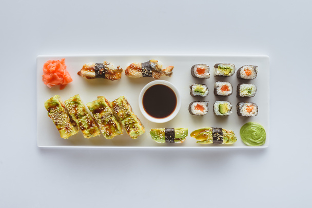 top view of delicious sushi set with ginger, wasabi and soy sauce isolated on white  - Foto, imagen