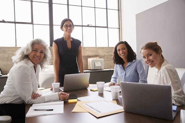 Four businesswomen in meeting room looking at camera - Foto, immagini