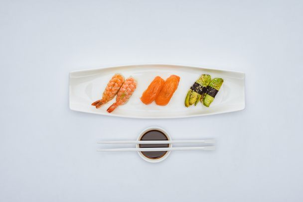 top view of gourmet sushi, soy sauce and chopsticks isolated on white - Φωτογραφία, εικόνα