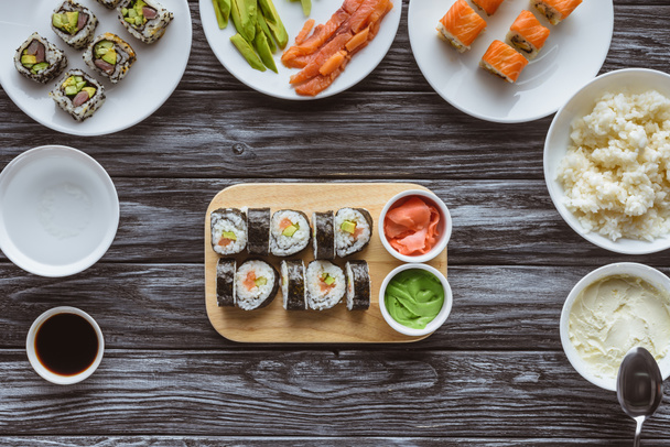 top view of delicious sushi rolls with ingredients on wooden table - Photo, Image