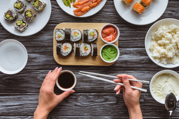 tiro cortado de pessoa segurando pauzinhos e comer sushi delicioso
 - Foto, Imagem