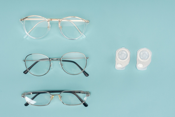 a szemüvegek és kontaktlencsék konténerek kék alapon szervezett felülnézet - Fotó, kép