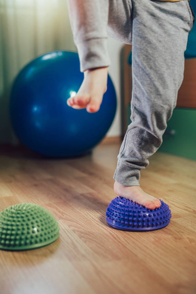 Flat feet correction exercise. Little boy walking over spiked half balance massage balls - Foto, imagen