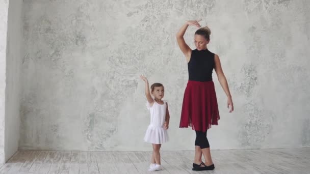 a small ballerina repeats the movements behind the teacher. ballet lesson in the studio - Footage, Video